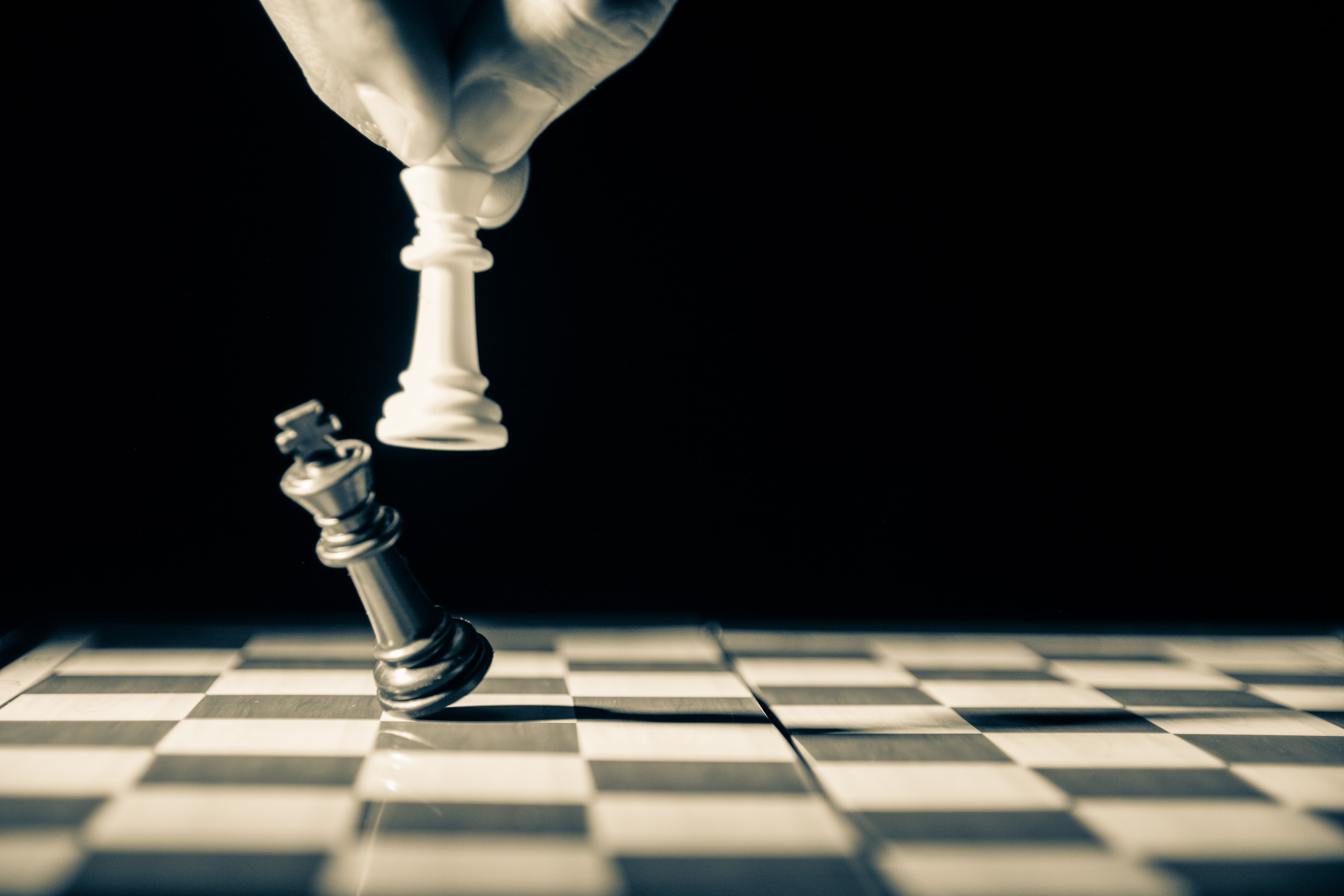 Stock image of a white chess piece knocking over a black chess piece.